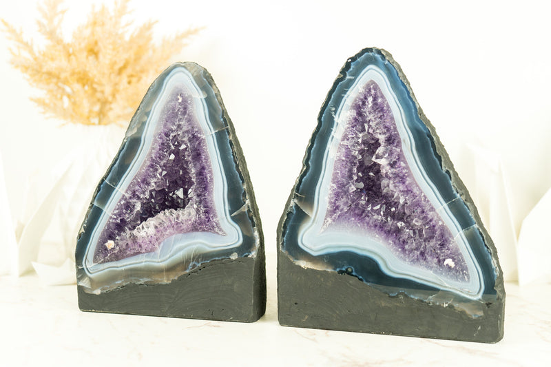 Paar buchgleiche Geoden aus blauem Spitzenachat mit Amethystkristall